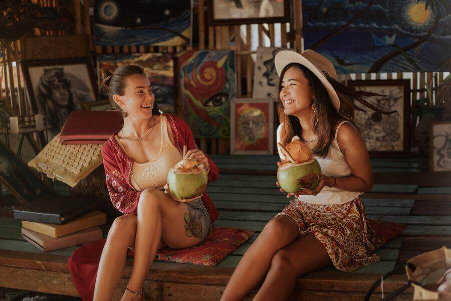 Friends traveling in Thailand drinking out of a fresh coconut